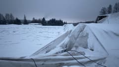 Lumen alta pilkistää romahtaneen kuplahallin rakenteita ja kangas kentän päällä