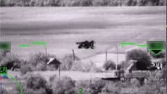Mustavalkoinen videokuva pellolta, jossa näkyy hieman panssarivaunua muistuttava maatalouskone.
