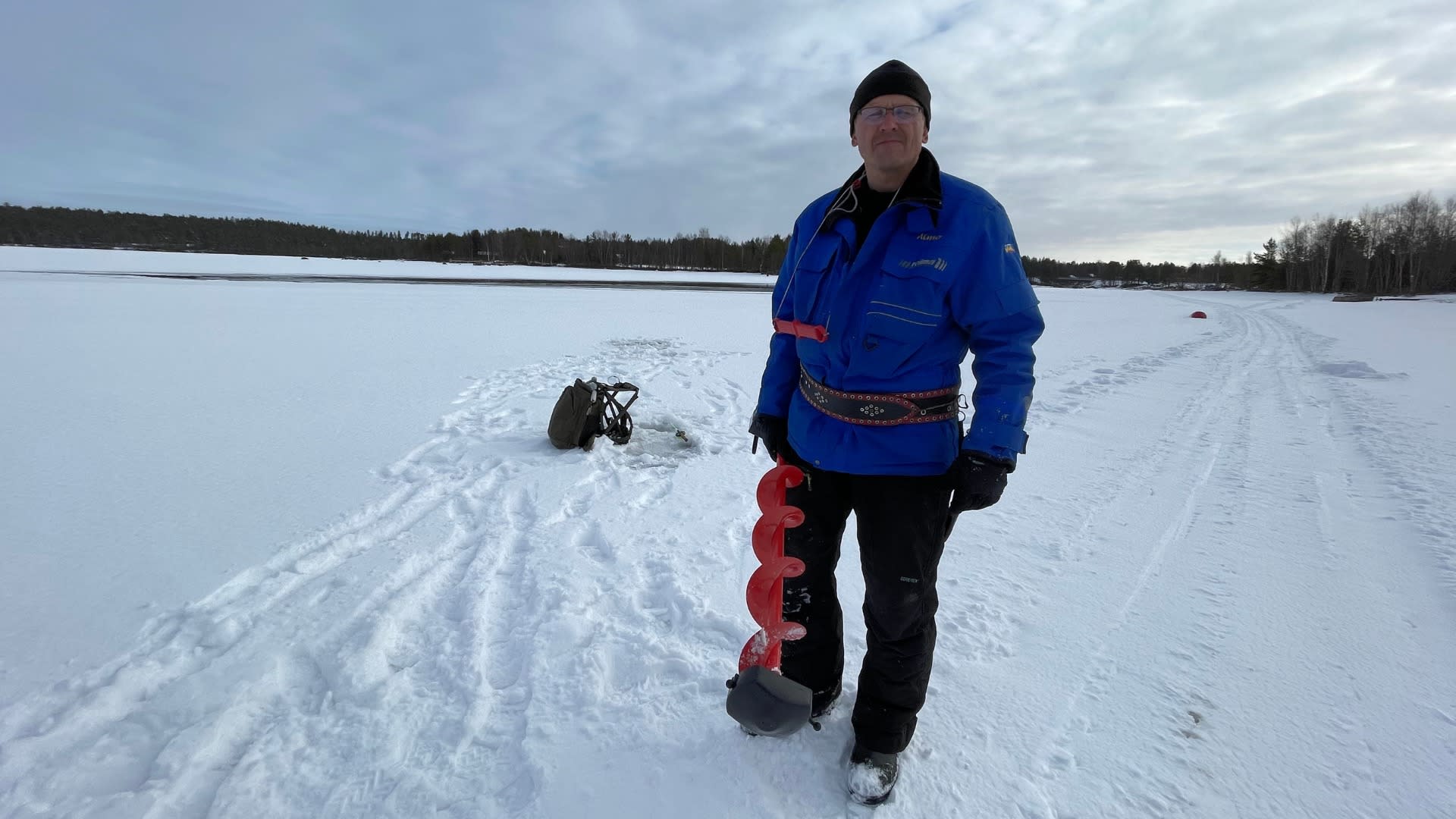 Nellimiläinen Aimo Koistinen mittaamassa jäätä Inarijärvellä huhtikuussa 2021. 