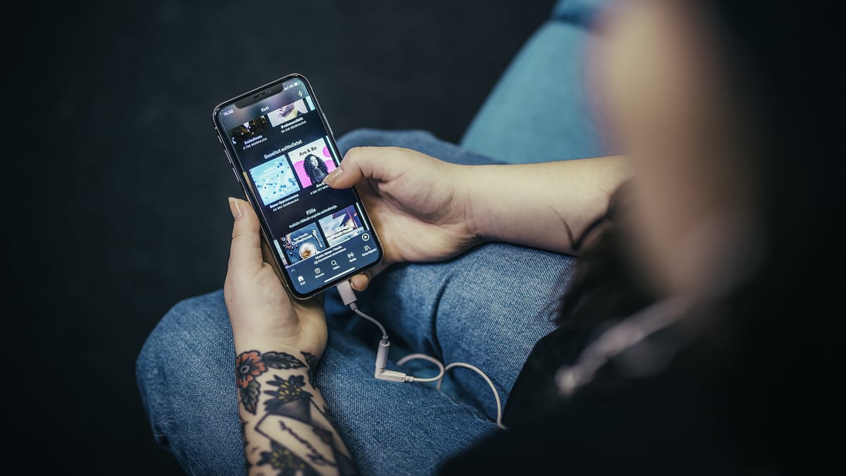 Puhelin kädessä sohvalla, Spotify auki.
