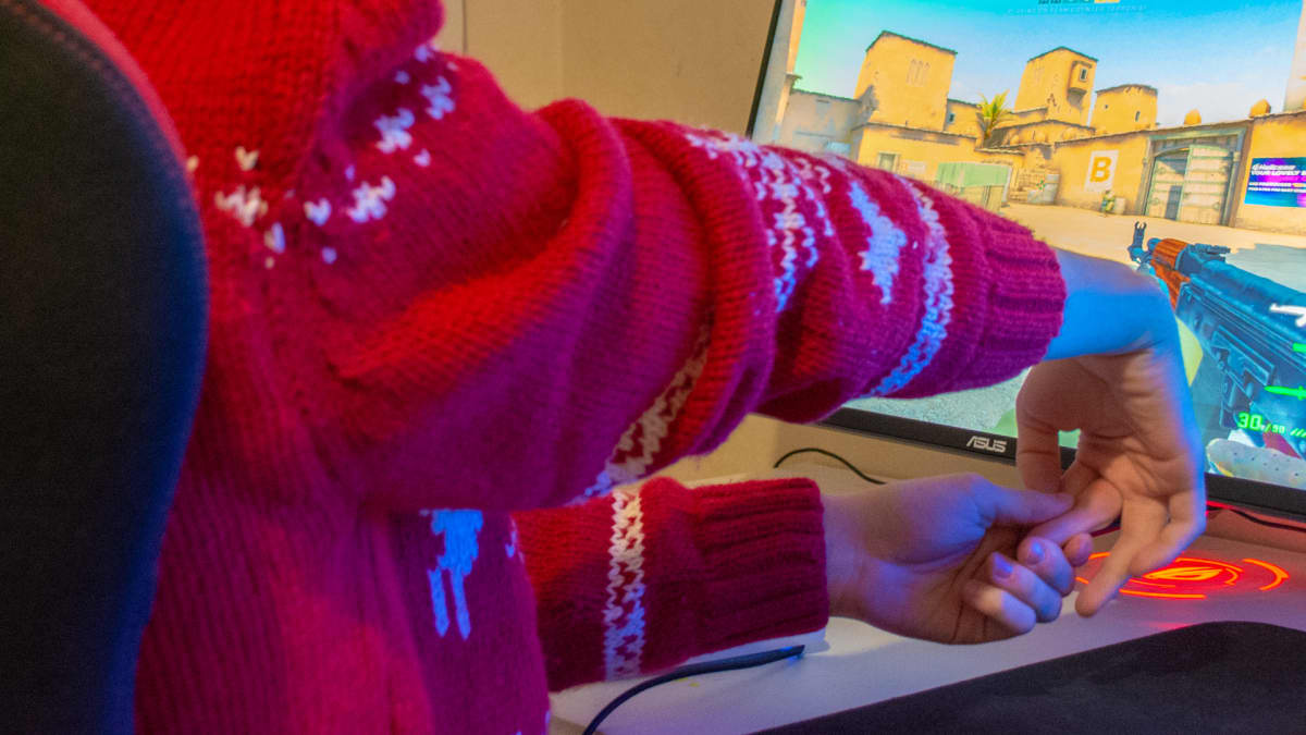 SJ Gamingin pelaaja Tuomas Louhimaa venyttelee rannetta tietokoneen ääressä.