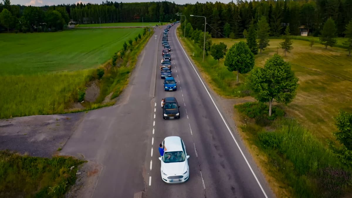 Maantiellä näkyy pitkä autoletka. 