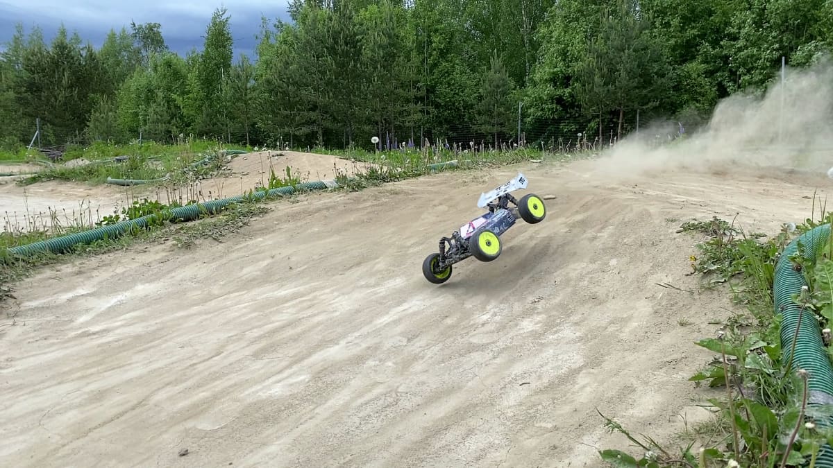 Rc-auto kiitää maastoradalla ja renkaista lentää pölyä
