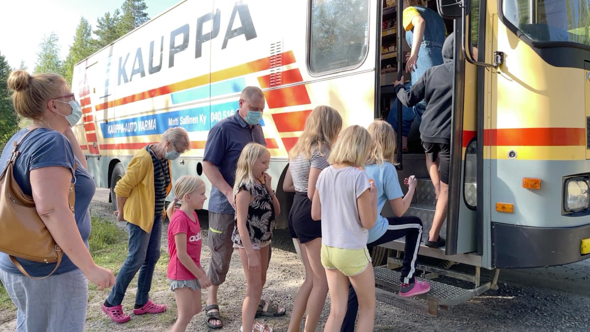 Ihmisiä nousee kauppa-autoon.