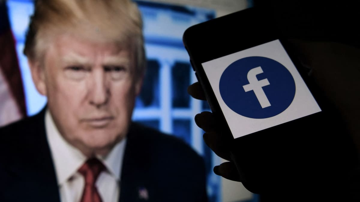Puhelimen ruudulla näkyy Facebooking logo, taustalla näkyy Donald Trumpin kuva näytöllä.
