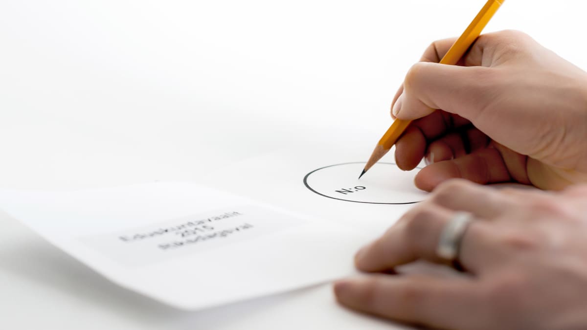 Nainen kirjoittamassa ehdokkaansa numeroa äänestyslipukkeeseen.