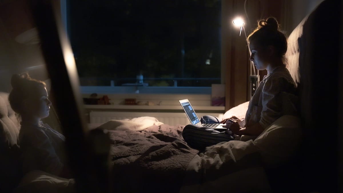 Suvi Saraiva istuu sängyllä ja on tietokoneella.