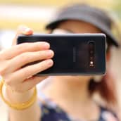 Nuori tyttö ottaa selfietä. Ojennettu kännykkä peittää kasvot.