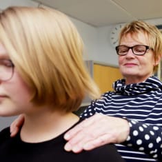 Koulufysioterapeutti tutkii kahdeksasluokkalaisen tytön hartioita.
