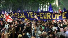 Mielenosoittajia kulkee Tbilisin kaduilla ison sinisen banderollin kanssa, jossa lukee "Kyllä Eurooppa".