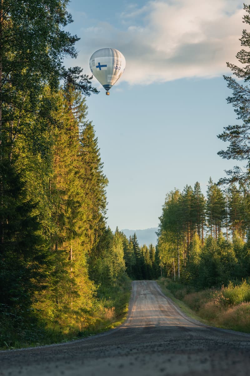 Kuumailmapallo lentää metsäautotien yllä.