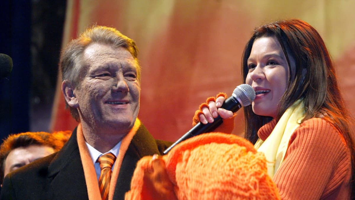 Viktor Juštšenko ja nainen puhumassa lavalla, molemmilla oranssia päällä. 