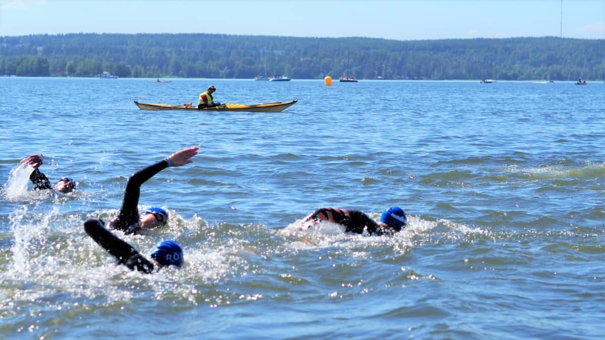 Kilpailijoita uimassa Vesijärvessä. Taustalla tarkkailija kanootissa.