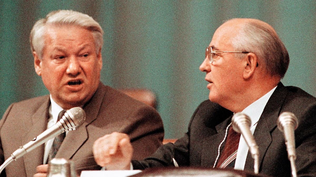 Jeltsin ja Gorbatshov istuvat pöydän takana, edessää mikrofoneja. Jeltsin sanoo jotain Gorbatshoville. Jeltsinillä on vaaleanruskea puvuntakki, Gorbatshovilla tummanruskea.