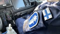 Poliisi istuu poliisiautossa.