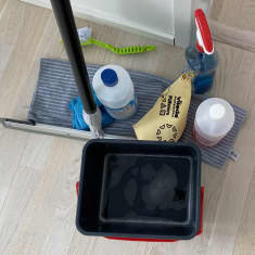 Siivoojan työvälineitä: ämpäri, rättejä, lattiankuivain ja puhdistusaineita. 