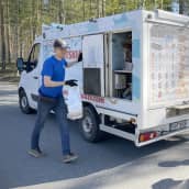 Jätskiauton myyjä Harri Taattola vie jäätelökassia autosta asiakkaille.