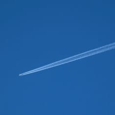 Lentokone taivaalla perässään tiivistymisjuova.