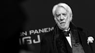Donald Sutherland katsoo kameraan tumma puku päällään.
