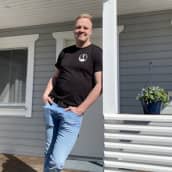 Mies nojailee kaiteeseen aurinkoisen talon terassilla.