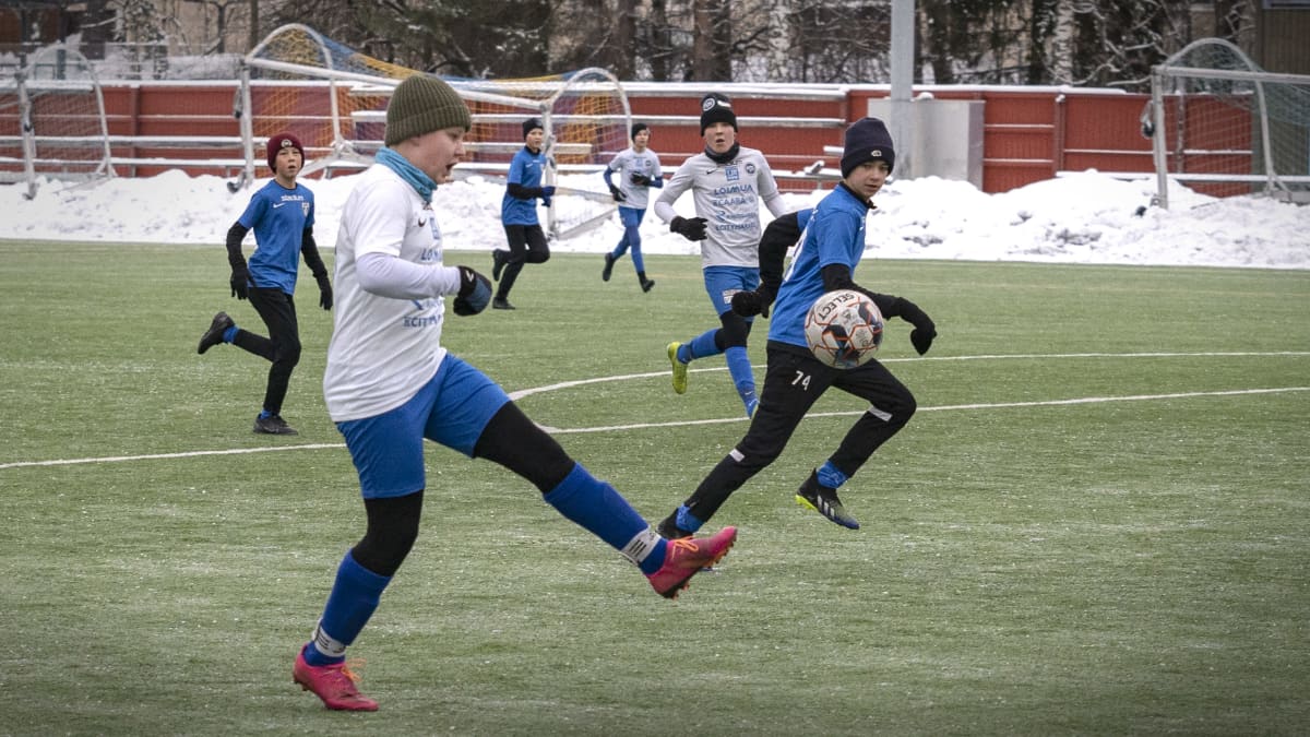 Lapset pelaavat jalkapalloa Oulunkylän urheilupuiston kentällä