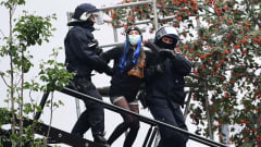 Kaksi poliisia taluttaa talonvaltaajaa alas tikkaita