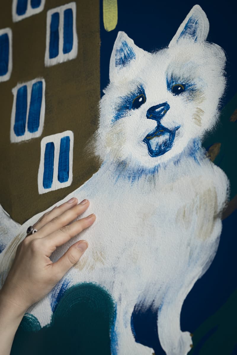 Käsi silittää seinään maalattua koiran kuvaa.