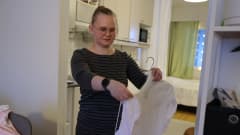 Oululainen Riitta-Liisa Kauppi laittaa vaatetta henkariin.
