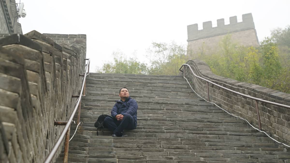 Wei Yong istuu Kiinan muurin portailla sumuisessa säässä