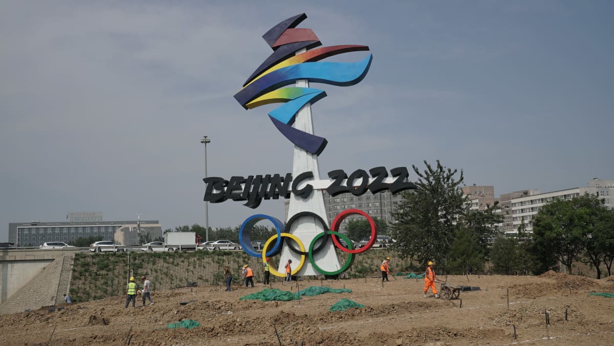 Työmiehiä työn touhussa Pekingin olympialaisten merkin luona.