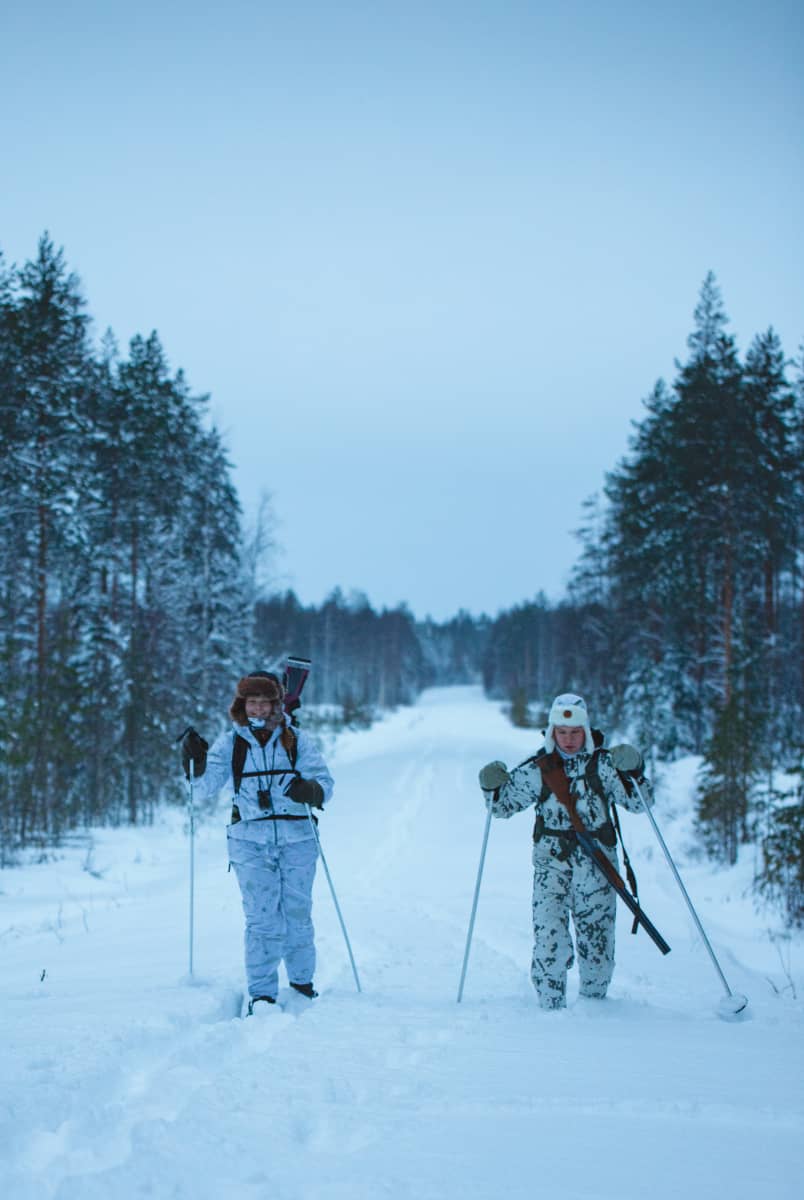 Nainen ja mies hiihtävät metsässä.