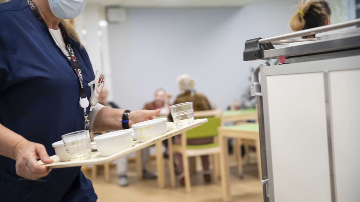 Hoitokodin työntekijä kuljettaa tarjotinta. 