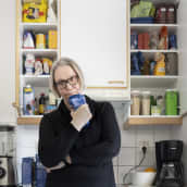 Anne Matilainen miettii keittiössä. Hän seisoo avoimien keittiön ruokakaappien edessä kädessään jauhopussi.