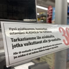 Kaupasssa kyltti jossa pyydetään todistamaan ikäraja ostettaessa alkoholia ja tupakkaa.