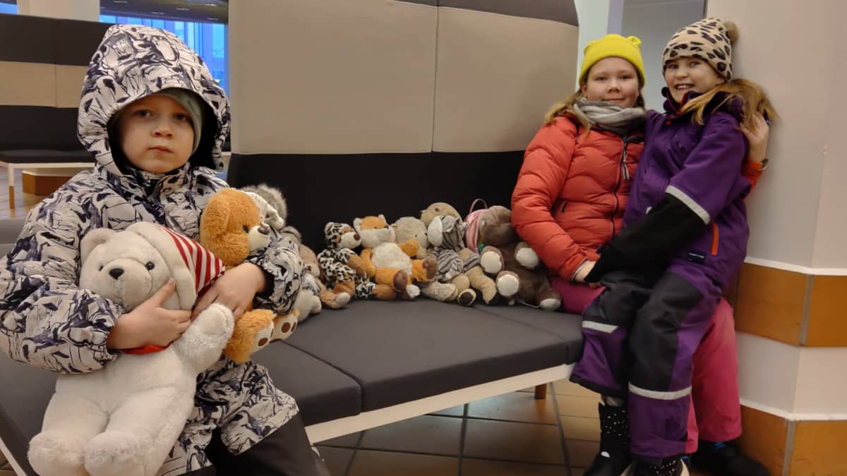 Espoolaiset Eino, Eevi ja Oona Sahanne pehmoleluineen Turun terminaalissa.