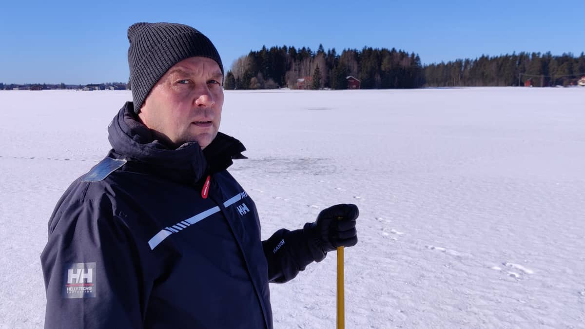 Mies seisoo lumisella pellolla ja katsoo vakavan näköisenä kohti kameraa.