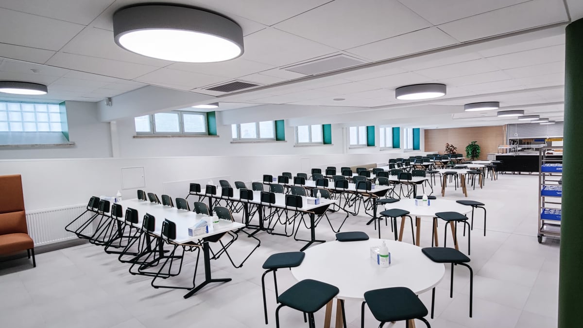 Koulun ruokalassa on avlkoiset pöydät ja mustat tuolit