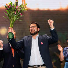 Ruotsidemokraattien Jimmie Åkesson tuulettaa kukkakimppu kädessään.