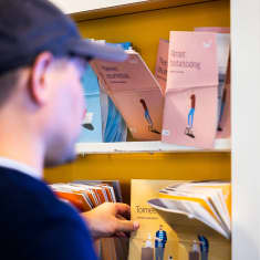 Henkilö katsoo Kelan esitteitä eri tuista.