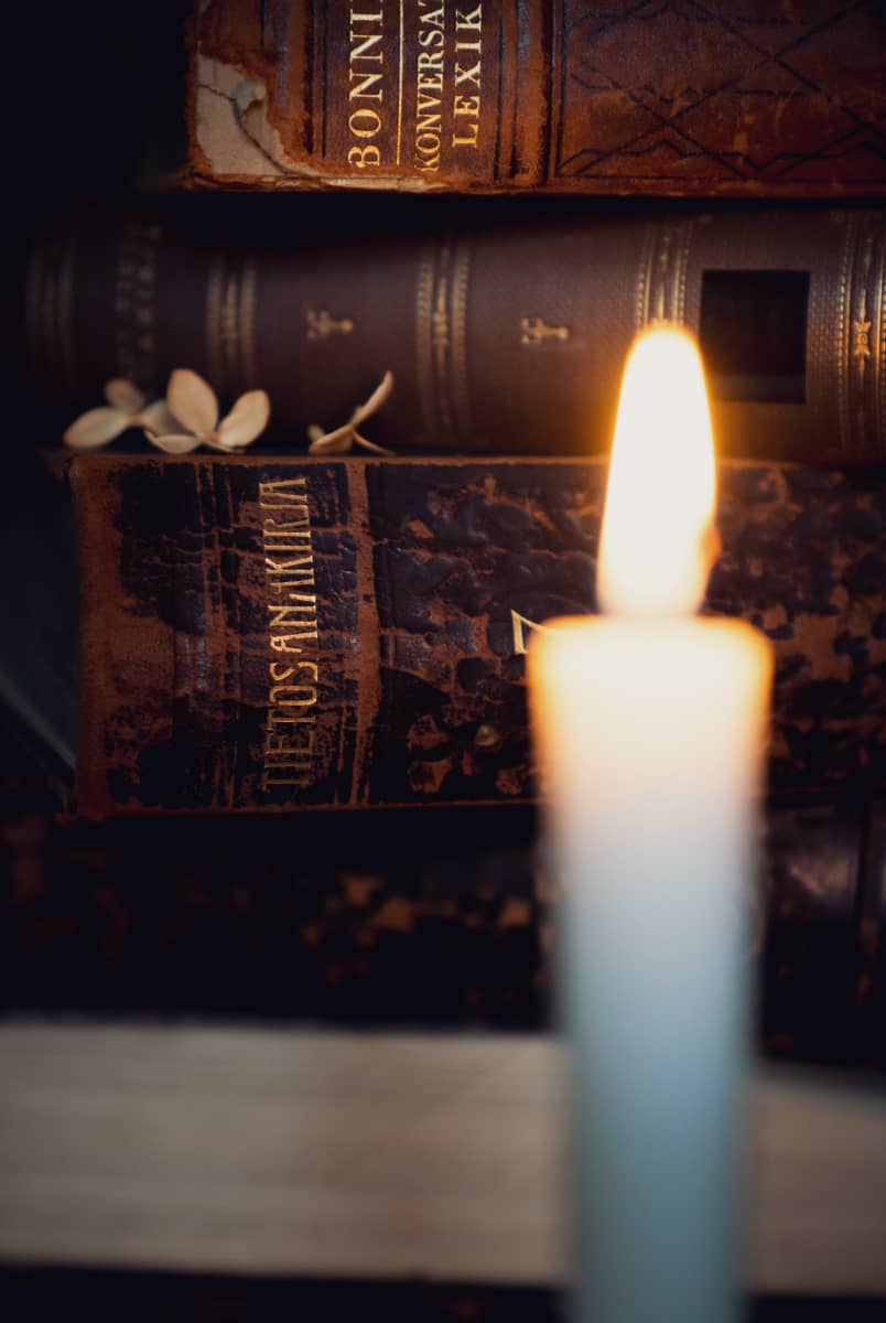 Lähikuva vanhasta tietosanakirjan kannesta kynttilän takana.