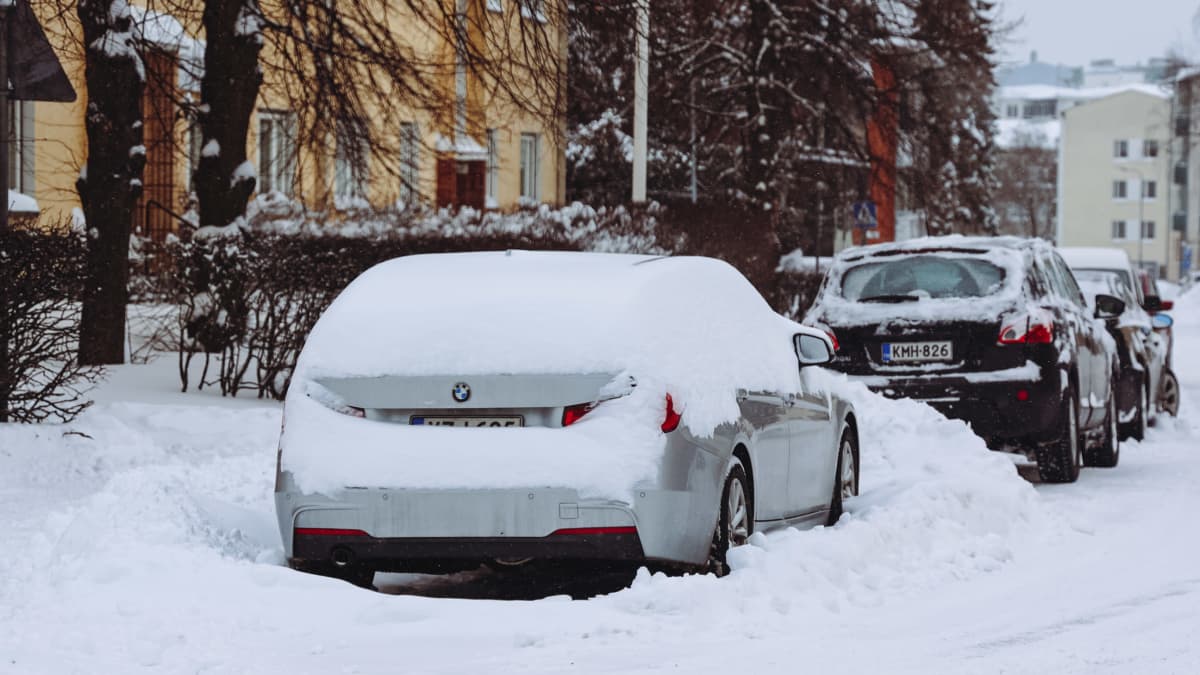 Harmaa auto kadunvarressa lumivallin keskellä Jyväskylässä.