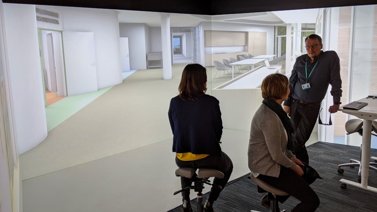 Joukko ylilääkäreitä ja ylihoitaja ovat tutustumassa suunnitteilla olevaan, uuteen Laakson yhteissairaalaan, 3D-huoneeseen projisoidun 3D-mallin avulla.