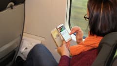 Nainen selaa nettiä kännykällään junassa.