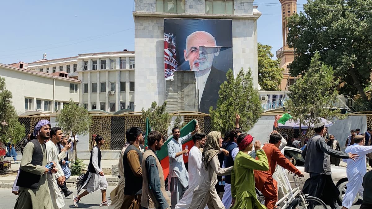 Afganistanilaiset juhlivat Afganistanin itsenäisyyspäivää Kabulissa, taustalla revitty juliste Afganistanin entisestä presidentistä.