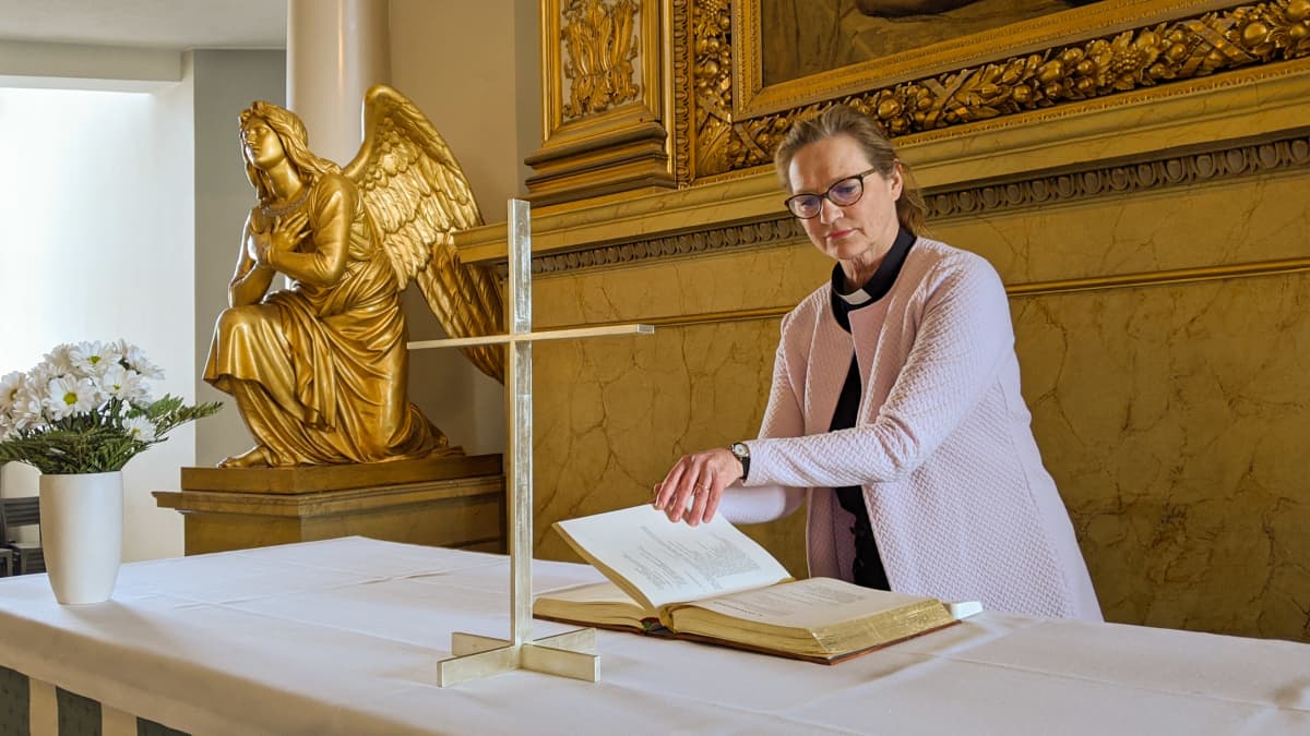Maija Kuoppala, kappalainen, katselee raamattua Tuomiokirkon alttarilla.