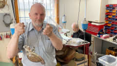 Kultaseppämestari Juha Janger pitelee käsissään hopeasta ja kivestä tehtyä isoa riekkoriipusta.