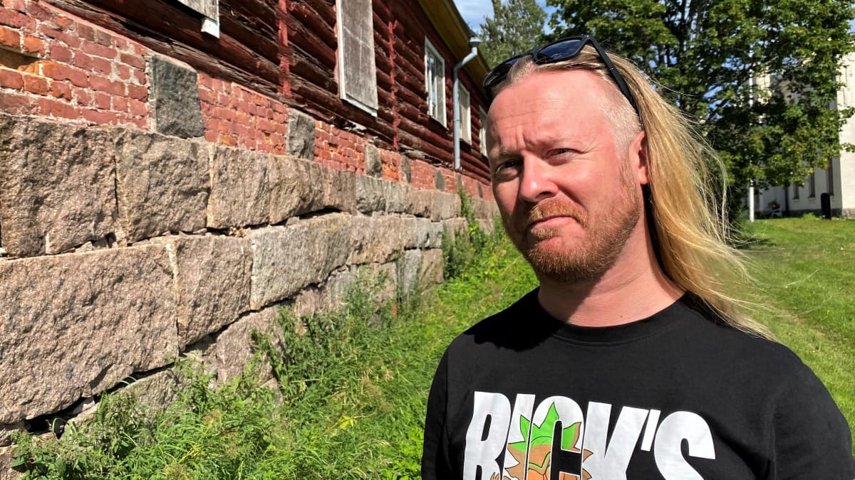 Antti Hyyrynen vanhan talon korkea kivijalan vieressä.