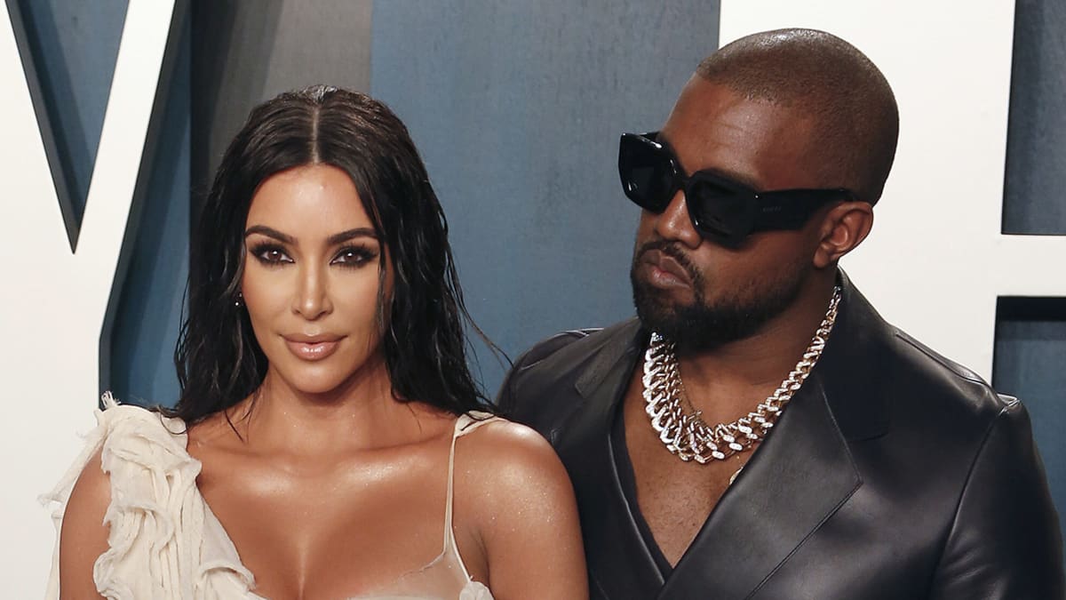 Kim Kardashian vaaleassa iltapuvussa ja Kanye West mustassa nahka-asussa
