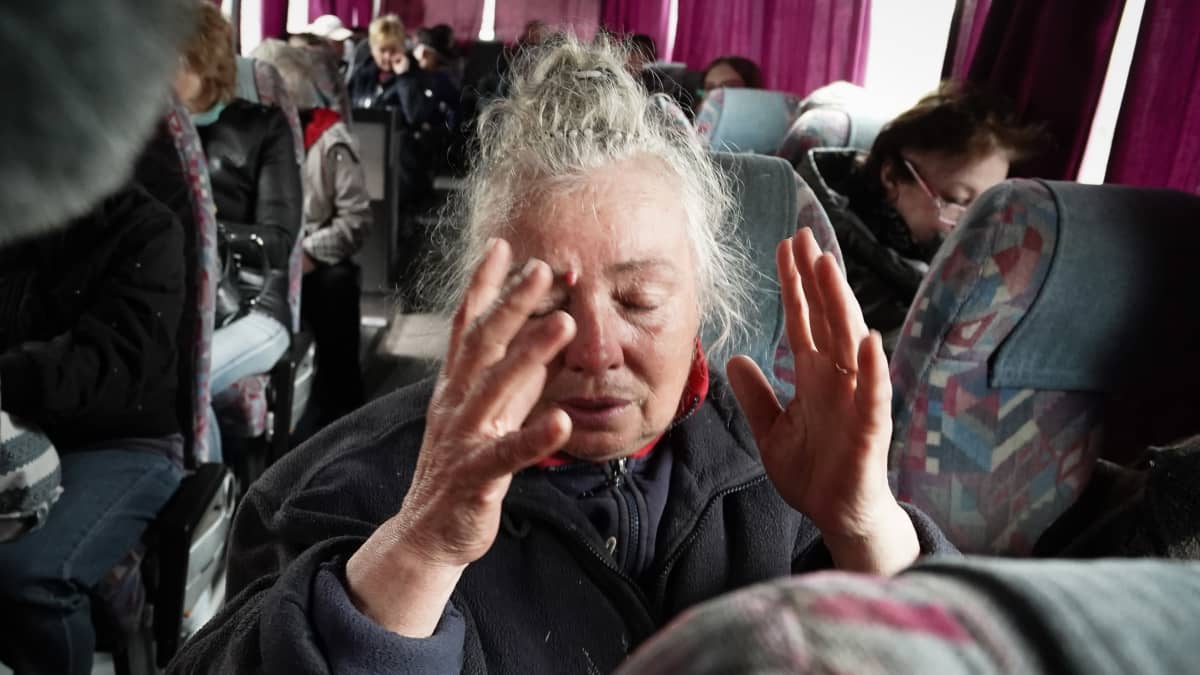 Nainen kohottaa käsiään bussin kyydissä.