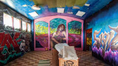 Ett rum med schackrutigt golv och muralmålningar på väggarna.